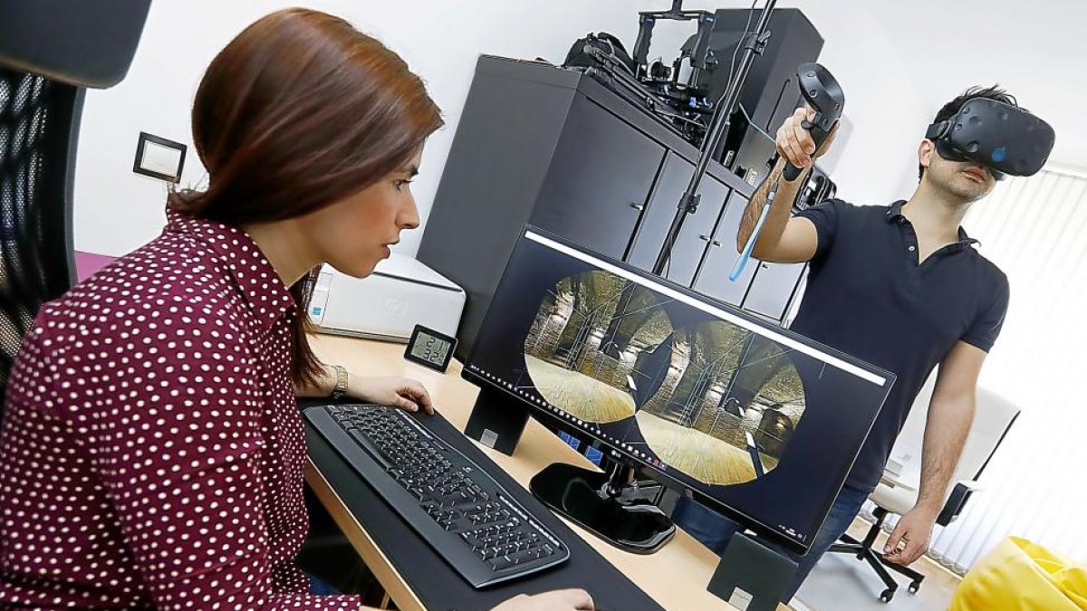 Almudena Cabezas muestra la recreación del túnel de una bodega, mientras que Pablo Sánchez lo contempla desde las gafas de realidad virtual.-J.M.LOSTAU