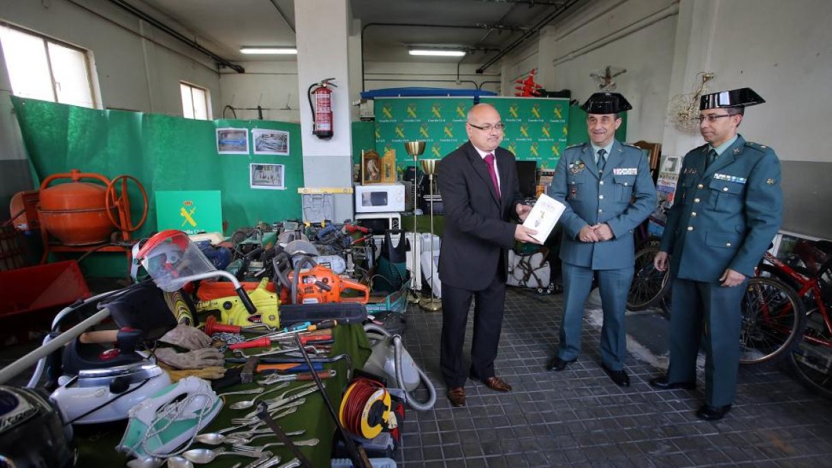 El subdelegado del Gobierno en Valladolid, Luis Antonio Gómez (I), muestra un ejemplar de El Quijote intervenido en el marco de la operación Valtri junto al teniente de la Comandancia de la Guardia Civil, Miguel Recio (D) y el comandante Roberto Ferrero-ICAL