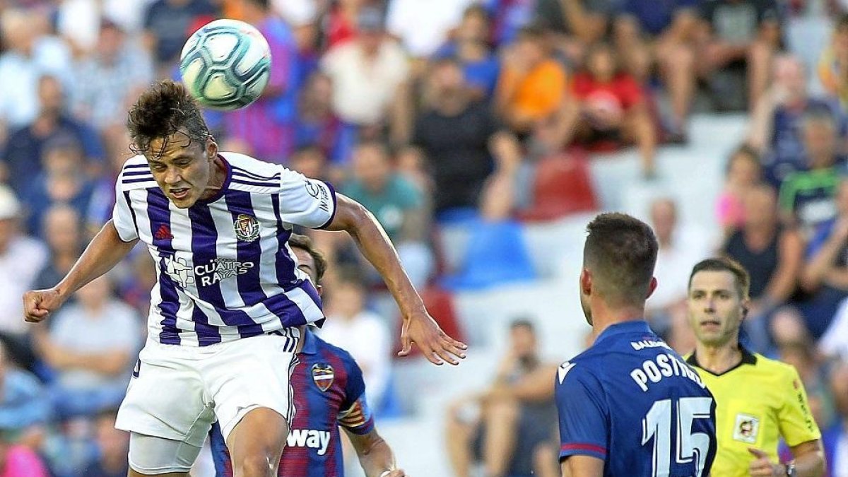 El delantero blanquivioleta Ünal remata de cabeza ante la mirada del central levantinista Postigo.-PHOTO-DEPORTE