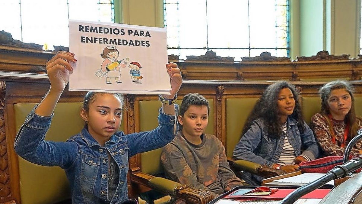 Una de las alumnas participantes en el pleno de la Infancia muestra un cartel durante la sesión.-E. M.