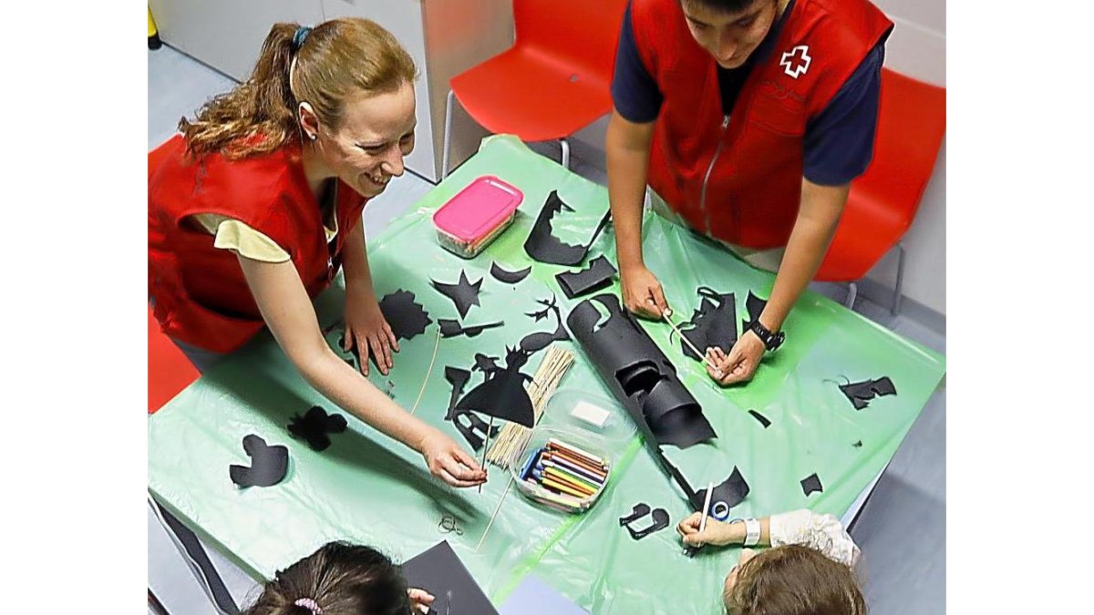 Imagen de voluntarios de Cruz Roja realizando actividades con niños hospitalizados.-J.M. LOSTAU