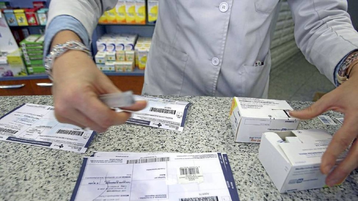 Una farmacéutica recorta el identificador del medicamento para pegarlo en la tradicional receta de papael.-Ical