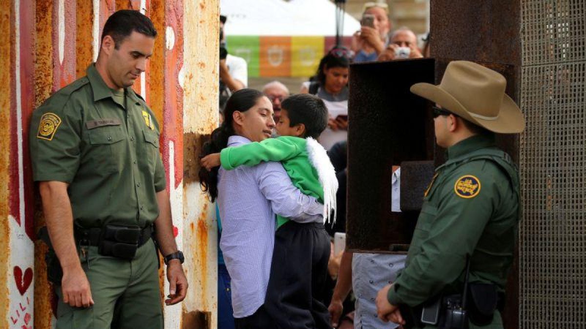Un hombre abraza a un niño en la frontera con México en California, el pasado 19 de noviembre.-REUTERS / MIKE BLAKE