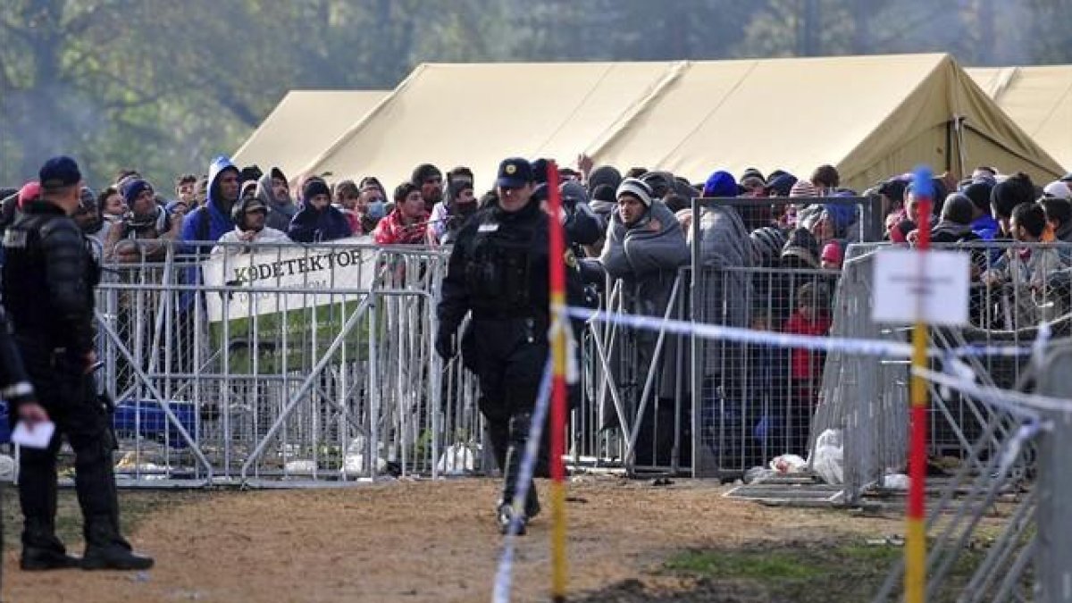 Refugiados controlados por agentes de policía en el saturado centro de acogida de Brezice, este miércoles.-EFE / IGOR KUPLJENIK