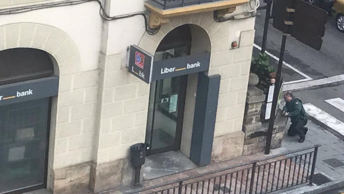 El asaltante burgalés, tendido en el suelo y herido, antes de ser detenido. Dentro del banco se refugió el mirandés.-ECB