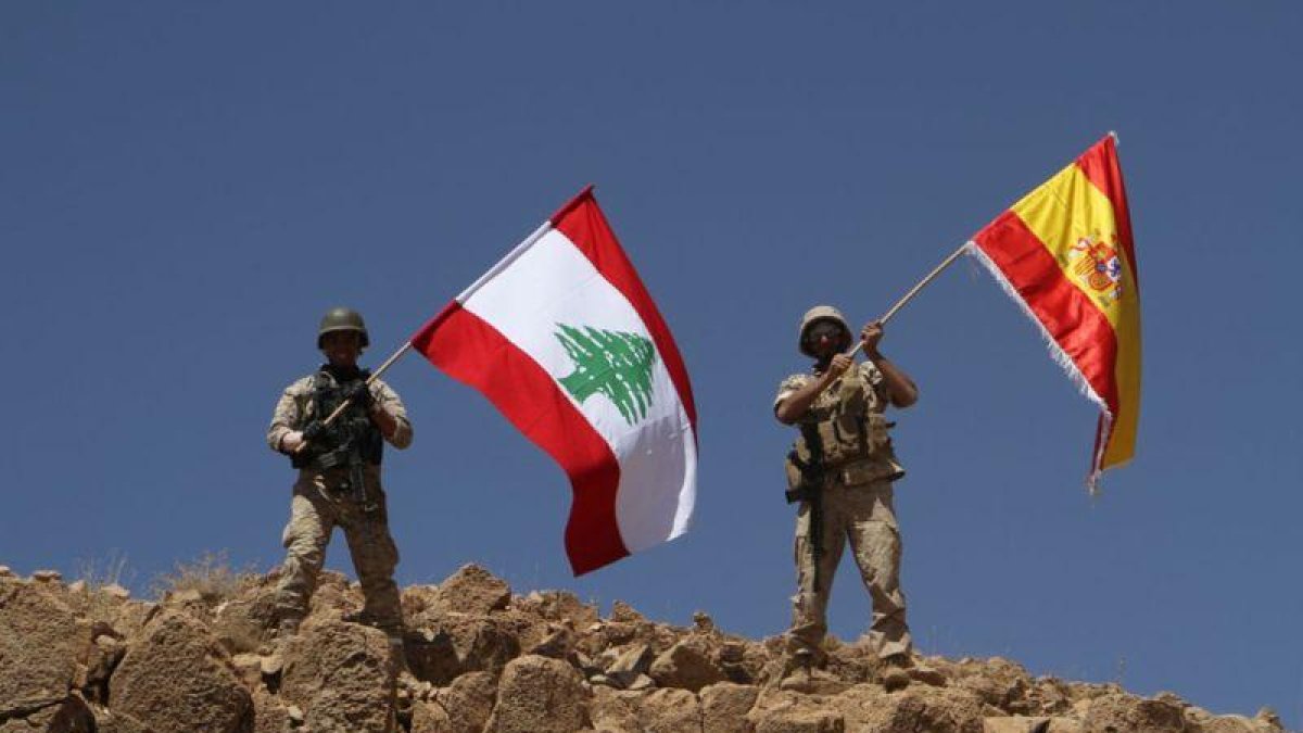 Dos soldados ondean las banderas libanesa y española tras recuperar parte de la región de Ras Baalbek.-HANDOUT (AFP)