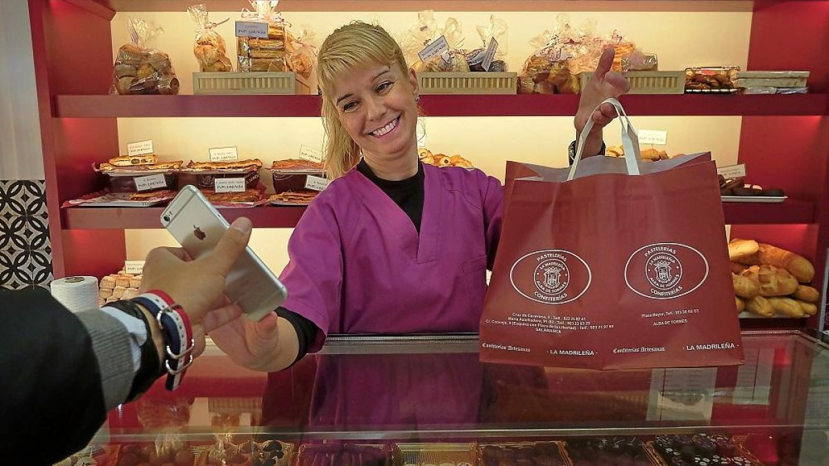 Una trabajadora de la pastelería La Madrileña entrega el lote a un cliente que previamente lo ha reservado a través del móvil.-ENRIQUE CARRASCAL