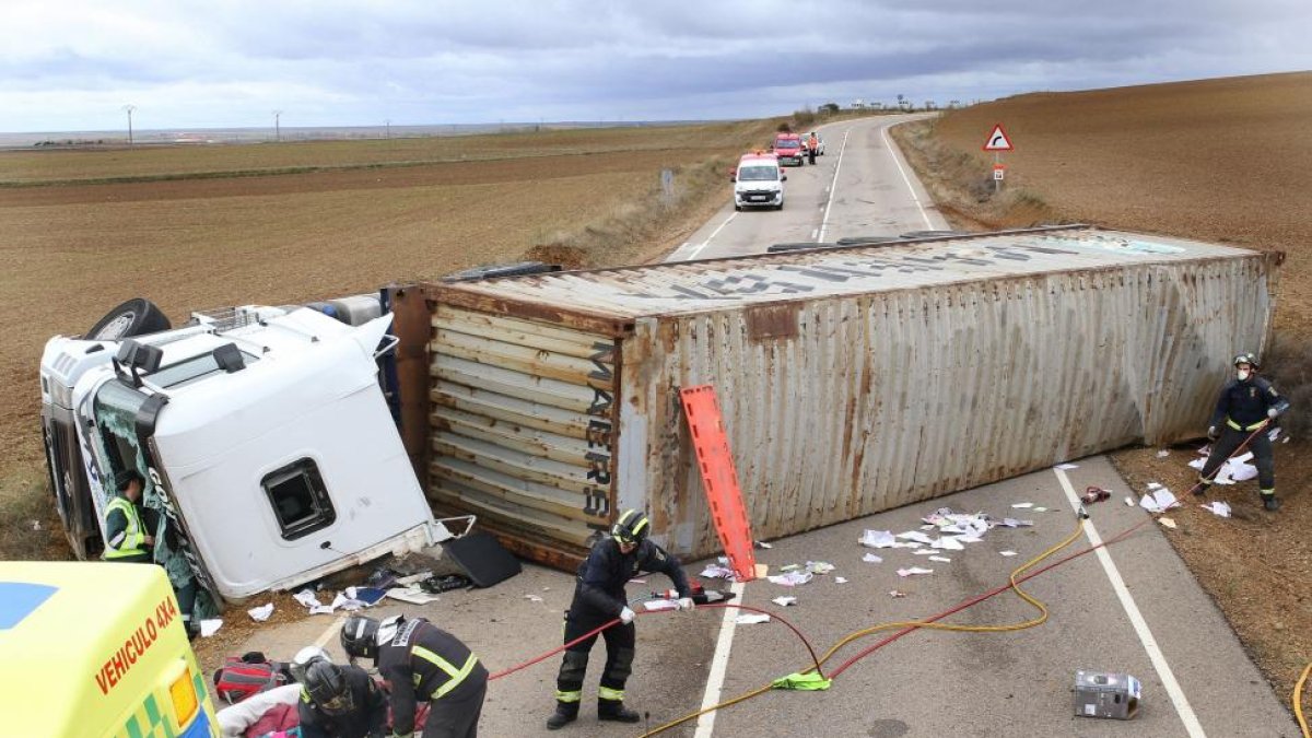Equipos de emergencia trabajan junto a un camión que ha volcado en la carretera autonómica CL-613, a la altura del municipio de Becerril de Campos (Palencia) y ha cortado ambos sentidos.-ICAL