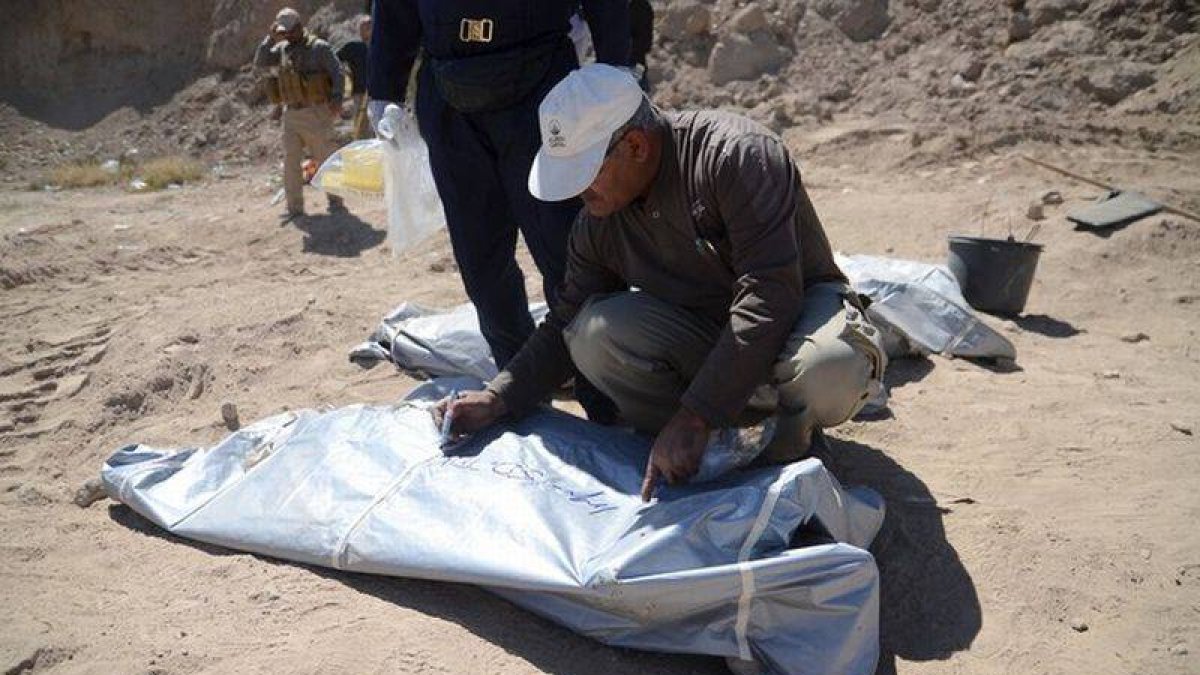 Un forense del ministerio iraquí de Sanidad escribe un número en la bolsa donde se ha colocado uno de los cadáveres localizados en fosas comunes en Tikrit.-Foto: STRINGER / REUTERS