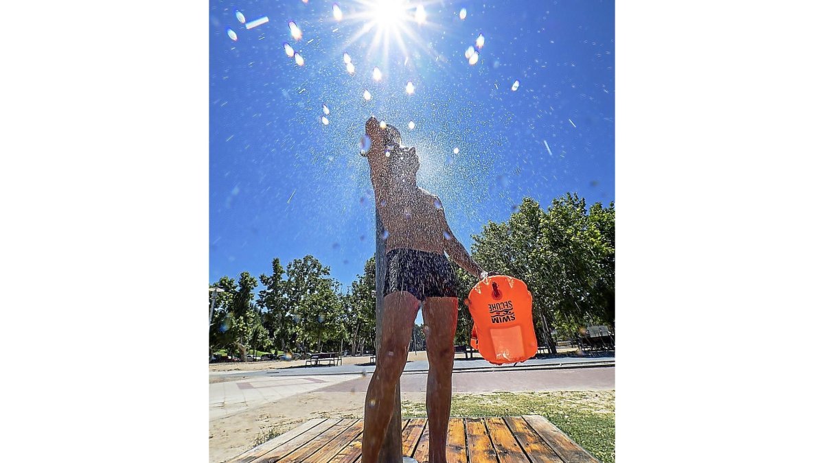 Un bañista se ducha en la playa de las Moreras, a orillas del Pisuerga, después de haber nadado en el río.-PABLO REQUEJO / PHOTOGENIC