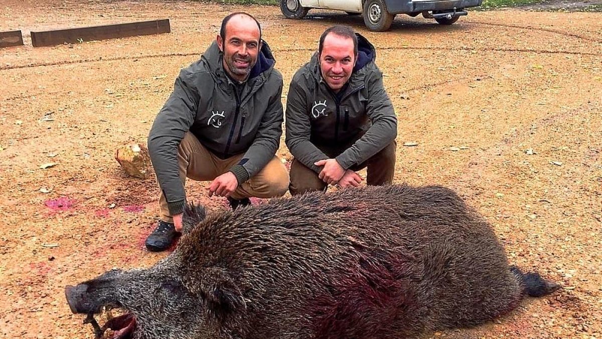 Los dos perreros, junto al jabalí que fue abatido.-LEONARDO DE LA FUENTE