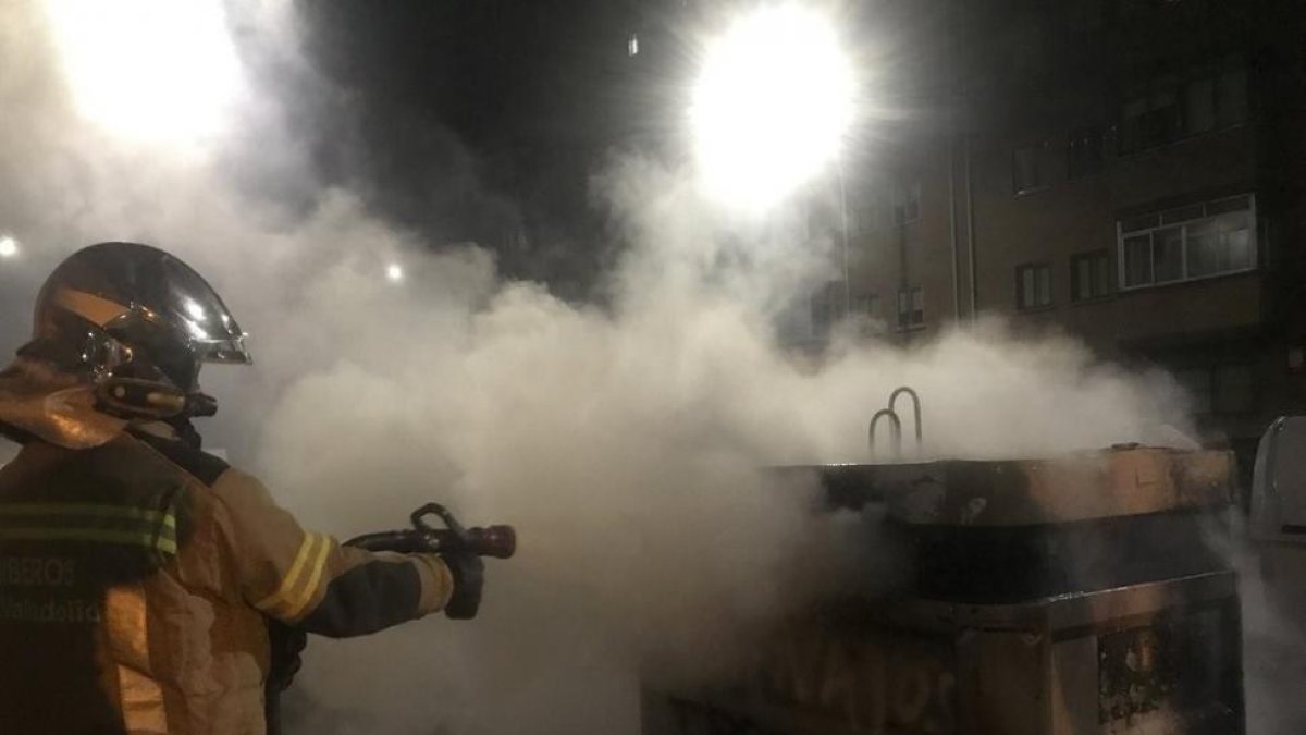 Un bombero extingue el fuego en uno de los contenedores.-TWITTER BOMBEROS