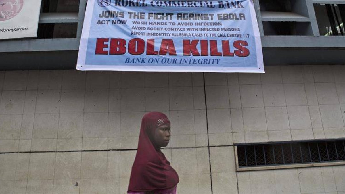 Una mujer pasa bajo un anuncio de alerta sobre el virus del Ébola en Freetown (Sierra Leona).-Foto: EFE / TANYA BINDRA