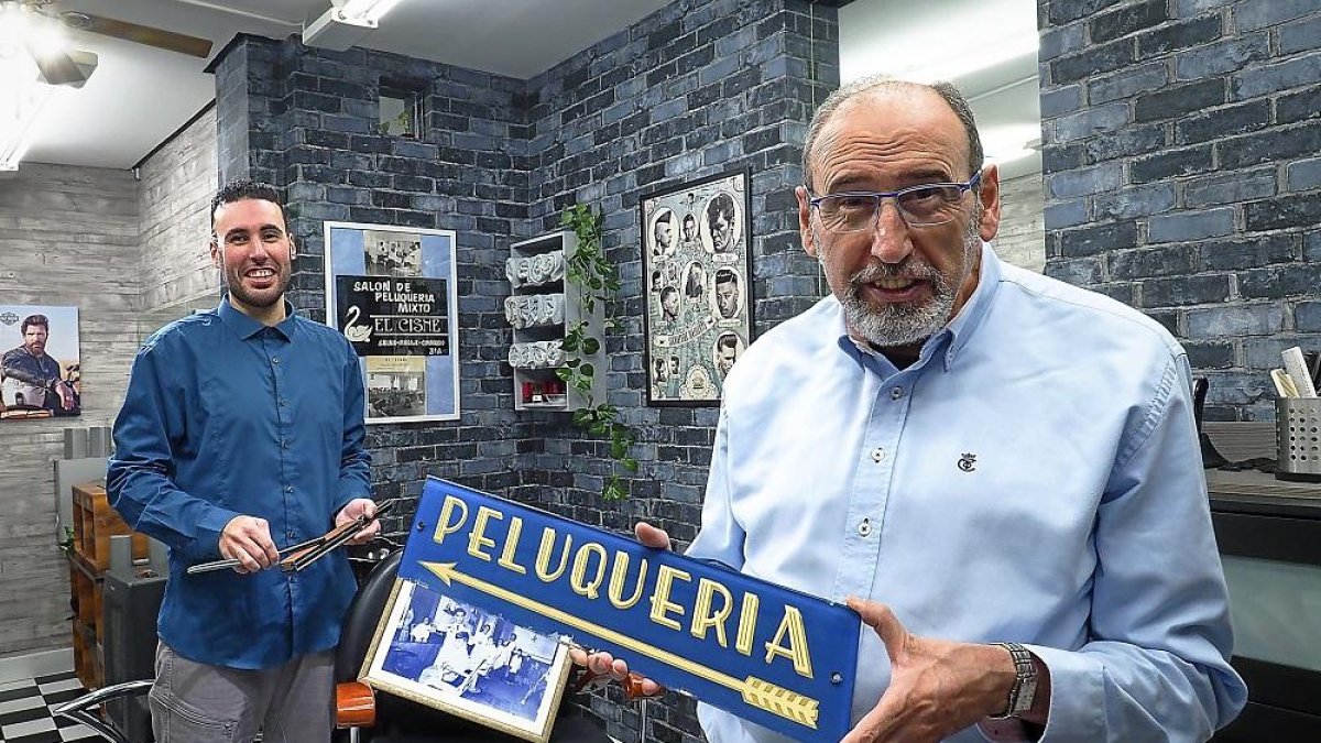 Fran junto a Paco Moreno, que sujeta el cartel de la peluquería de su abuelo, Don Francisco.-MIGUEL ÁNGEL SANTOS / PHOTOGENIC