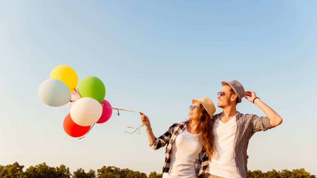 Una pareja riendo con globos.-123RF