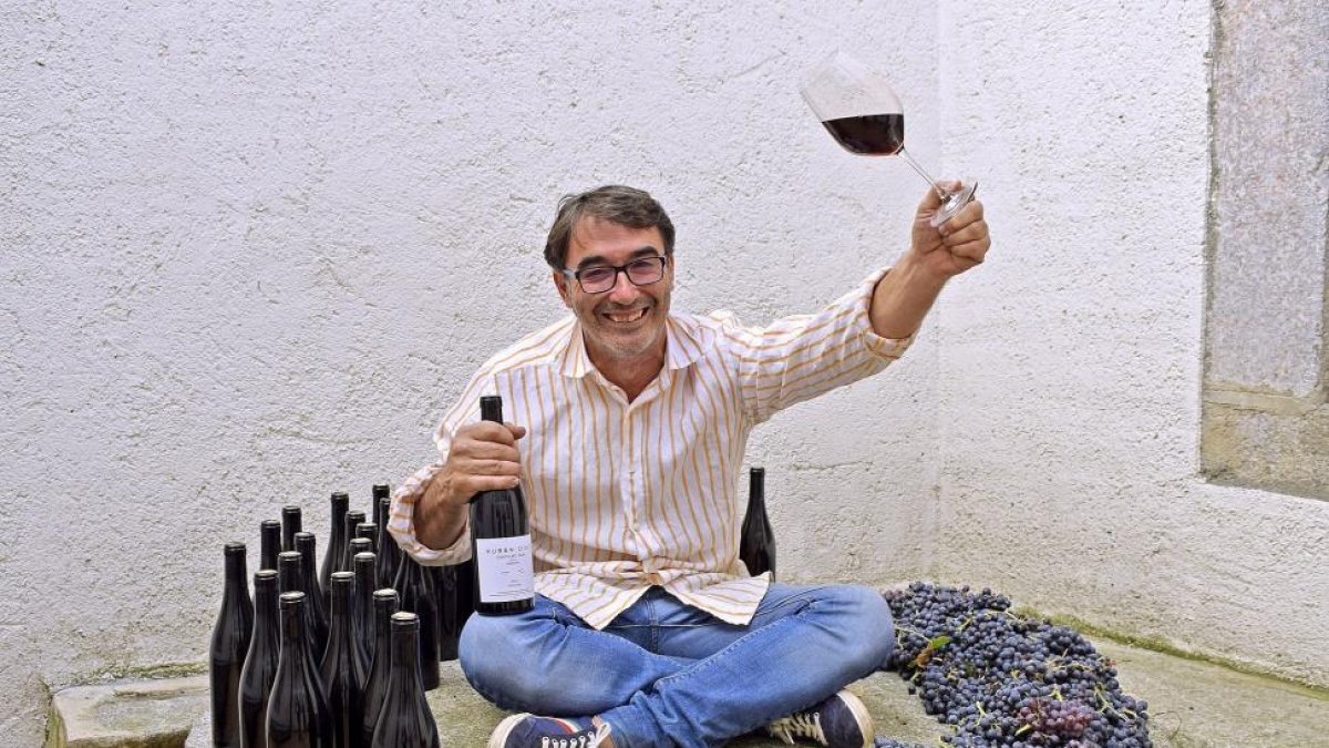Jaime Díaz, con sus vinos y varios racimos de garnacha, cimiento varietal de su trabajo en Cebreros.-ARGICOMUNICACIÓN