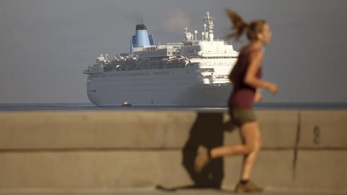 Una mujer corre por el Malecón mientras el crucero Thomson Dream llega a La Habana, el 19 de marzo.-AP / DESMOND BOYLAN