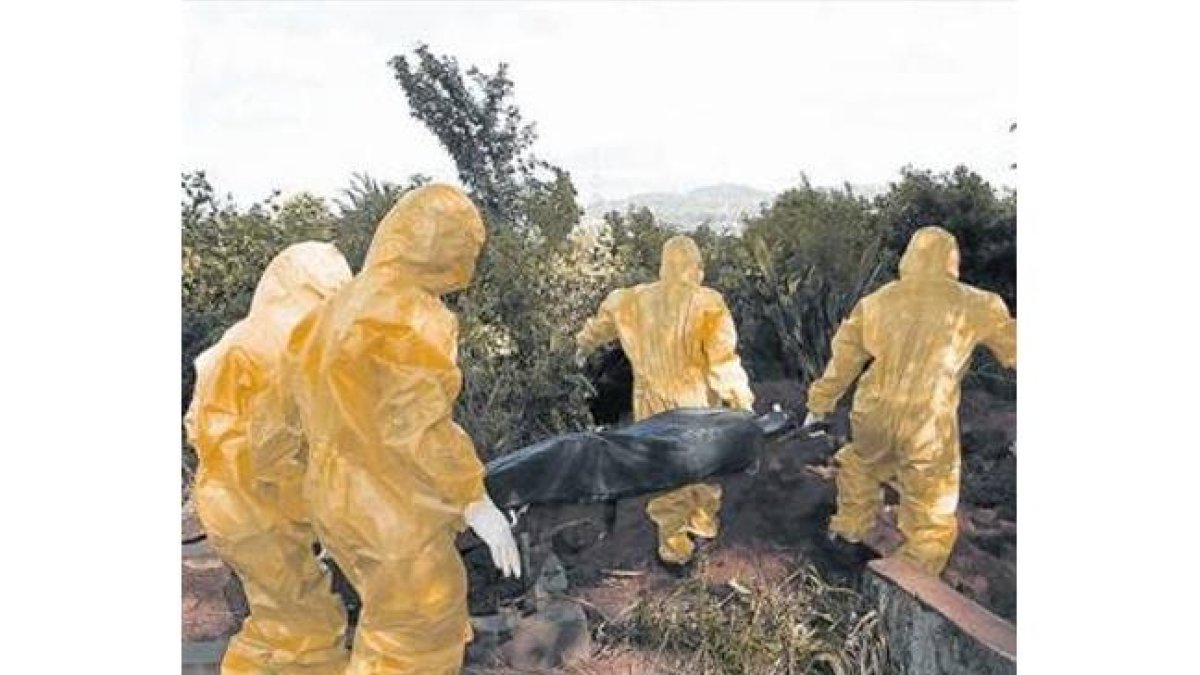 Personal sanitario con trajes de aislamiento traslada el cuerpo de una posible víctima de ébola en Sierra Leona.-Foto: REUTERS / CHRISTOPHER BLACK