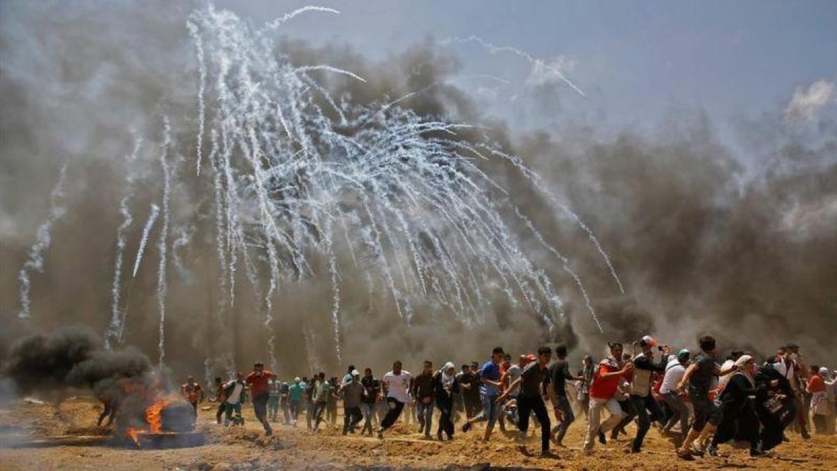 Los palestinos huyen de los gases lanzados por soldados israelís en Gaza.-AFP / MOHAMMED ABED
