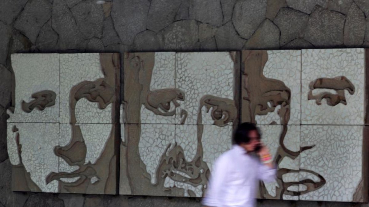 Un hombre pasa frente a un muro con los retratos de tres de los seis jesuitas asesinados en El Salvador en 1989, este miércoles.-REUTERS / JOSÉ CABEZAS
