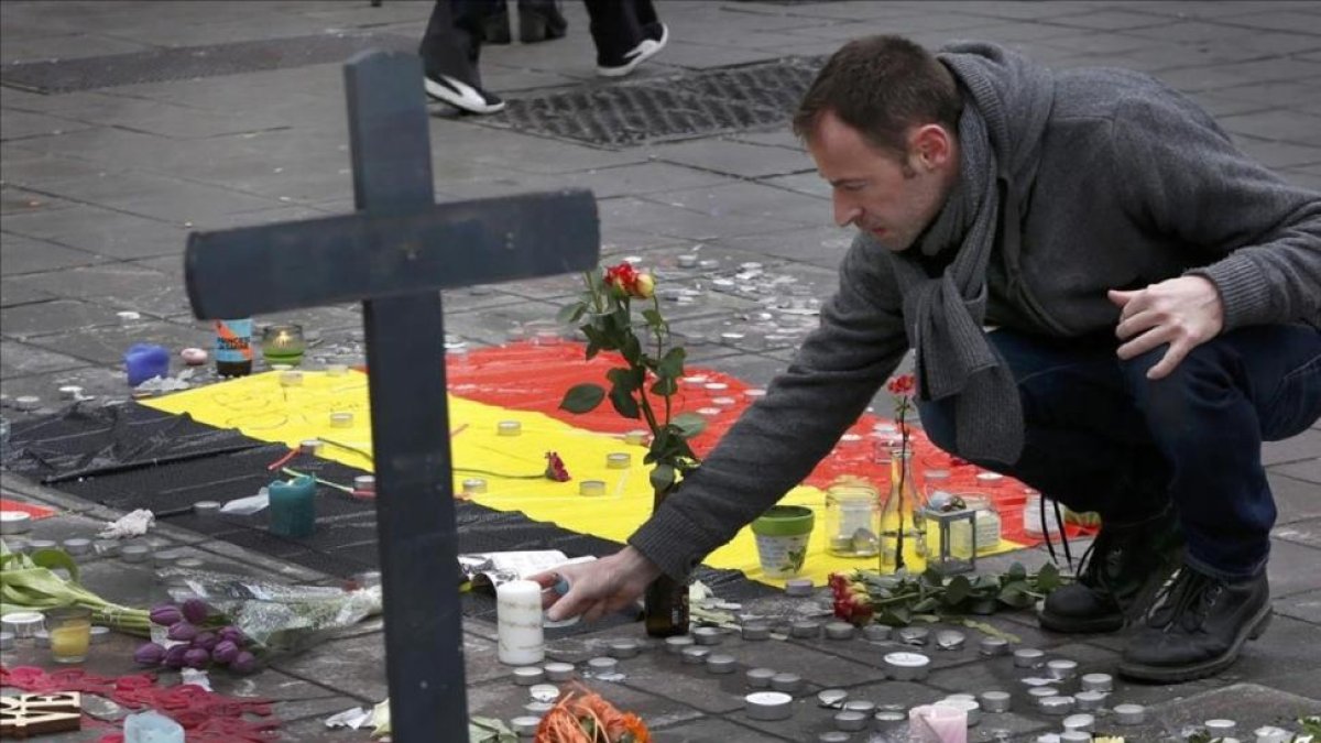 Un hombre deja flores en el tributo a las víctimas de los atentados de Bruselas-FRANCOIS LENOIR