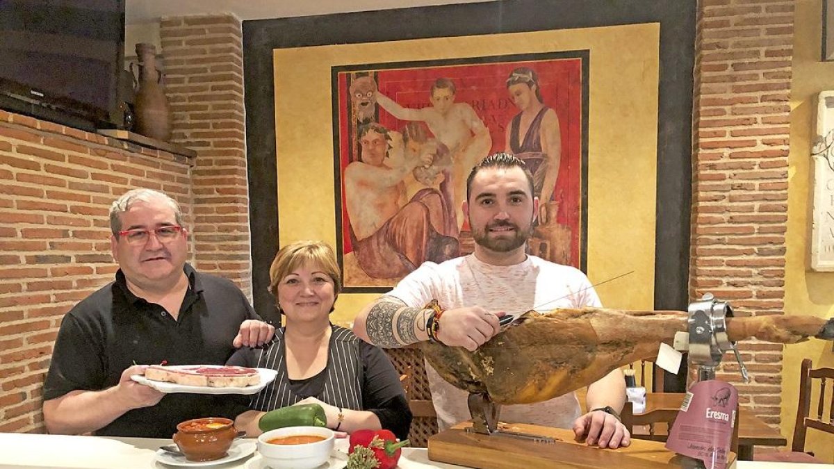 De izquierda a derecha, Jesús Galindo, Pilar Merino y su hijo, Pedro José, en el interior del restaurante La Muralla, delante de uno de los frescos que lo decoran.-ARGICOMUNICACIÓN