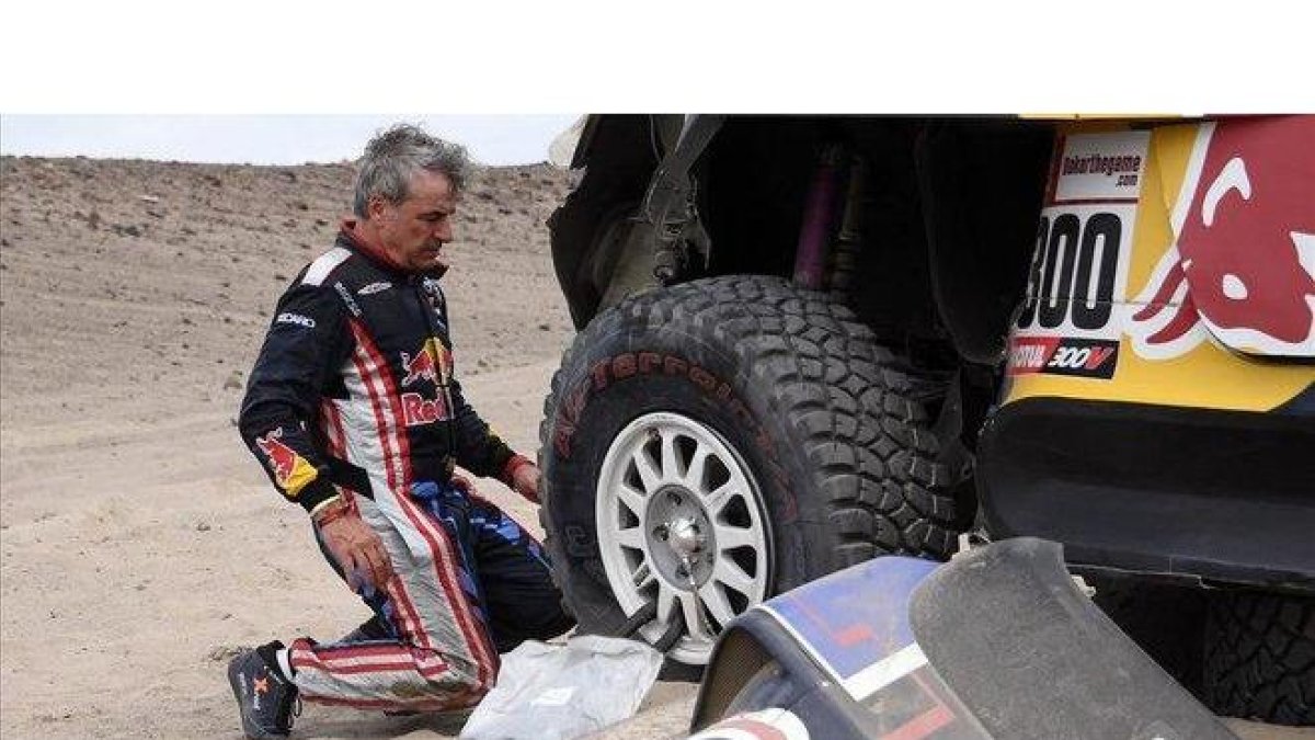 Carlos Sainz (Mini), en pleno trabajo para cambiar una rueda pinchada.-AFP / FRANCK FIFE