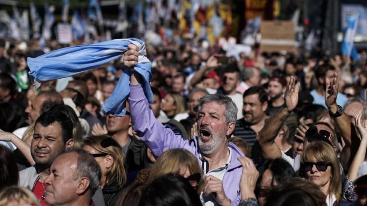 Un hombre empuña la bandera argentina entre la multitud que ha tomado las calles de Buenos Aires para protestar por la situación económica del país.-VICTOR R. CAIVANO (AP)