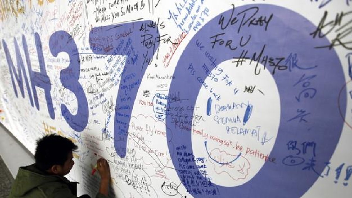 AUS01. KUALA LUMPUR (MALASIA), 30/07/2015.- Fotografía de archivo del 13 de marzo de 2014 de un hombre escribiendo mensajes en honor a las víctimas del vuelo MH370 de Malaysia Airlines en el aeropuerto internacional de Kuala Lumpur (Malasia).-EFE/MAK REMISSA