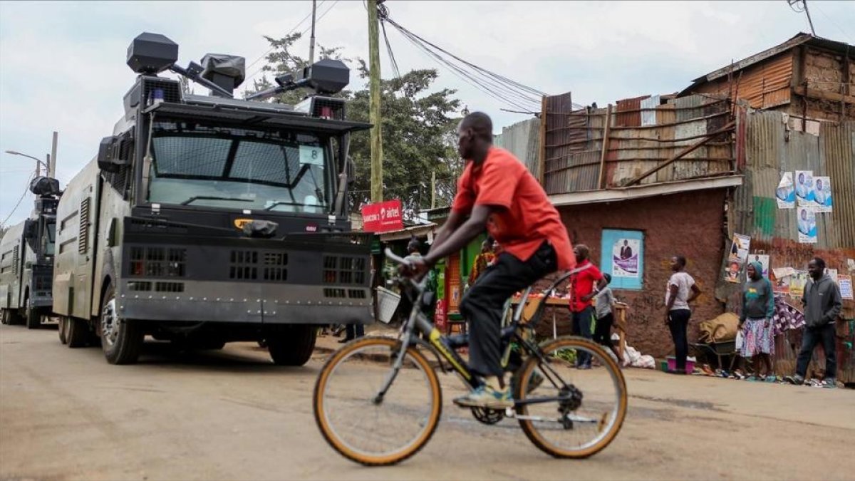 Un ciclista pasa por delante de un vehículo antidisturbios en las chabolas de Kibera, en Nairobi, el 7 de agosto.-REUTERS