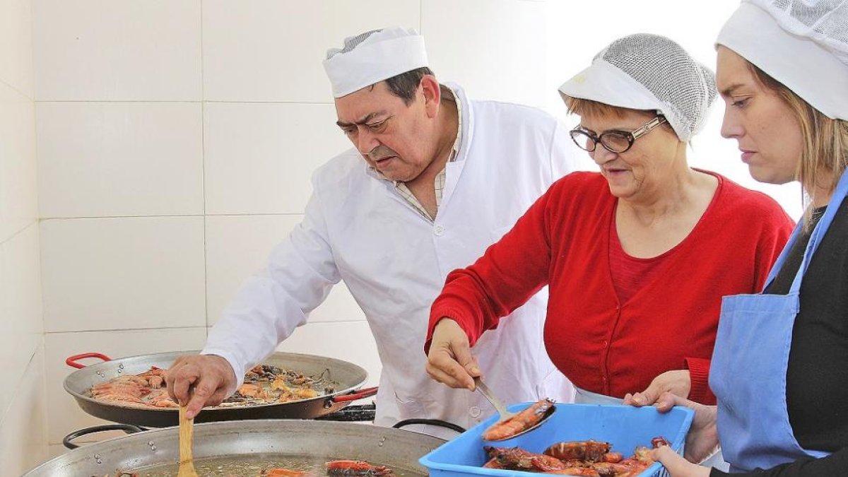 En la imagen, el matrimonio formado por Adela Calleja y Pedro José de Prada supervisan la preparación del arroz con bogavante que elaboran en el establecimiento junto a una de sus hijas.-J.L. CABRERO