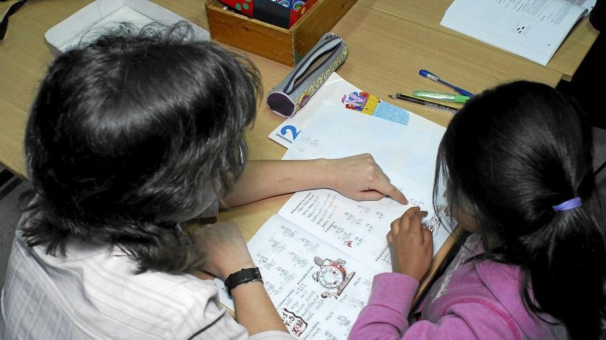 Una especialista presta apoyo escolar a una alumna, en una fotografía de archivo.-E. M.