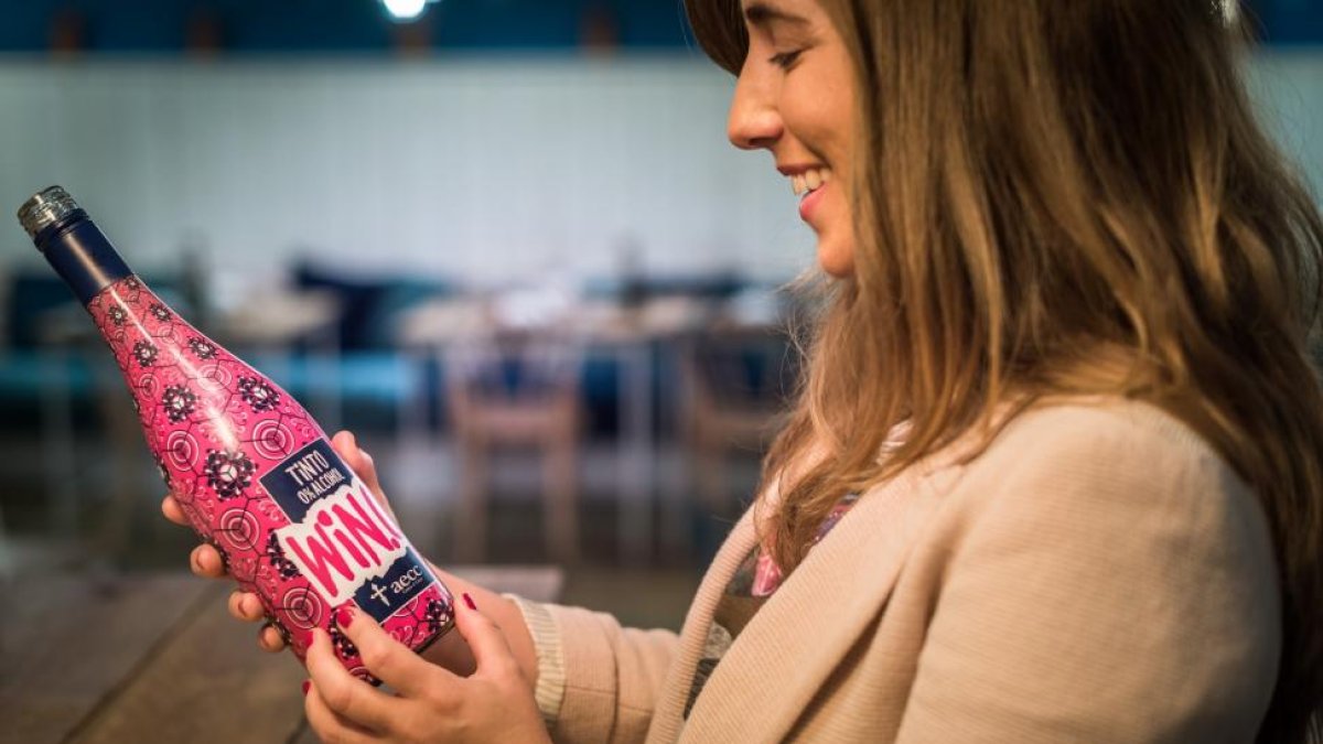 Una mujer oberva una botella del vino solidario.-ICAL