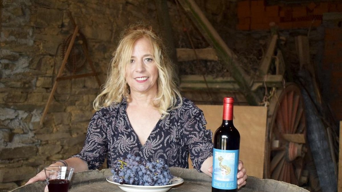 Teodora López en el interior de la bodega familiar con un racimo de uvas de tinta mencía y el primer vino que se embotella en su pueblo.-E. M.