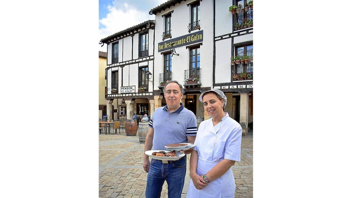 Quelín Rodrigo, con la típica olla podrida, y la cocinera Ángela Marrón, en la Plaza Doña Urraca de Covarrubias, ante Casa Galín.-ARGICOMUNICACIÓN