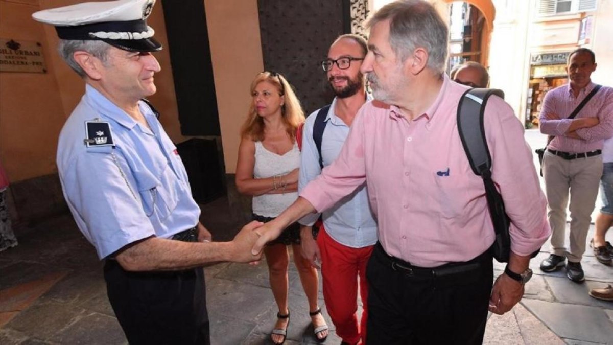El nuevo alcalde de Génova, el conservador Marco Bucci (centro), saluda a un policía local a su llegada al Palazzo Tursi, sede de la alcaldía de Génova, el 26 de junio.-