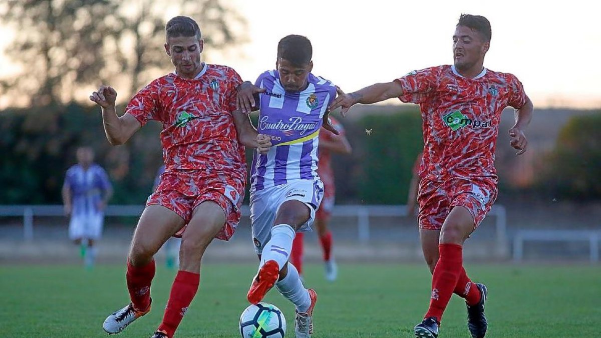 Iban Salvador se abre paso entre dos jugadores del Guijuelo, con su peculiar segundo uniforme.-ENRIQUE CARRASCAL