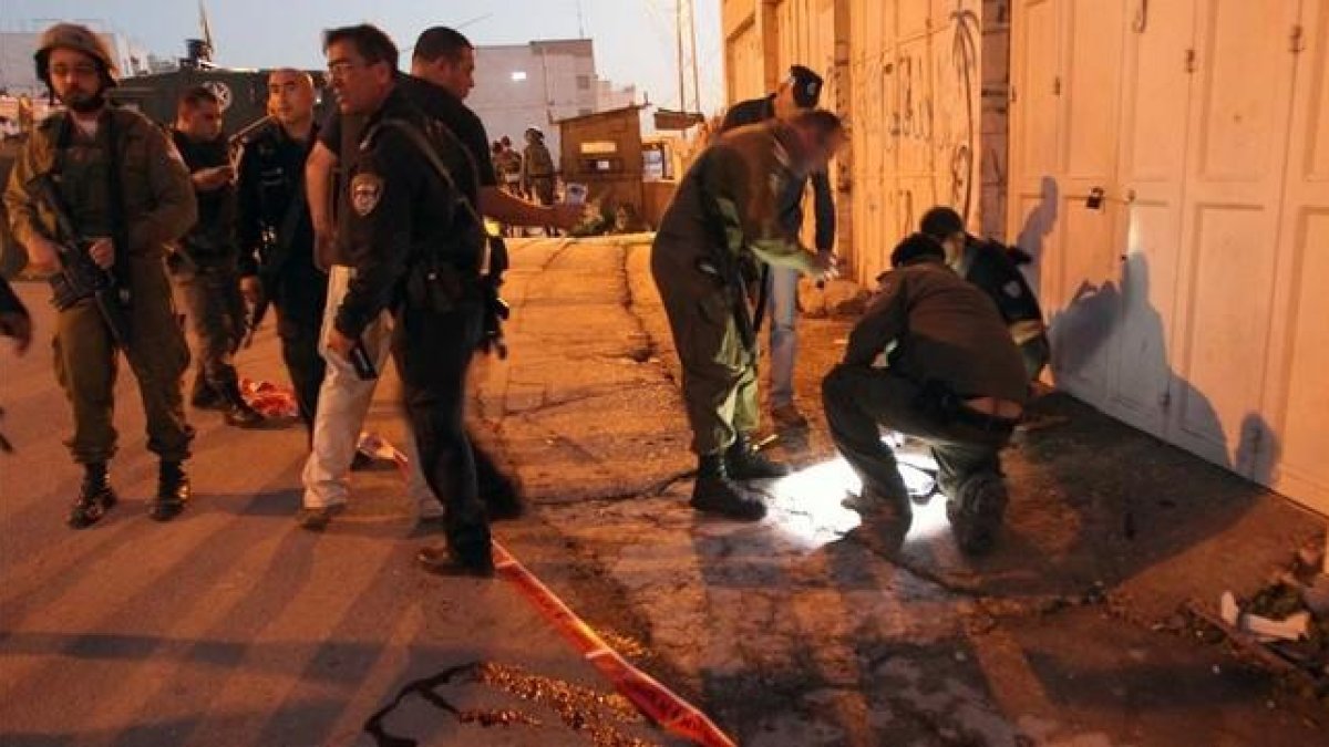 La policía israelí trabaja en el lugar donde cayó mal herida la adolescente palestina en Hebrón.-AFP / HAZEM BADER
