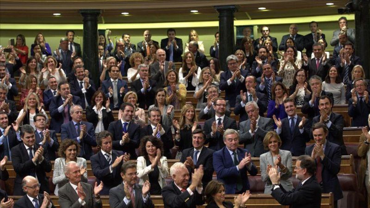 El líder del PP, Mariano Rajoy, aplaudido por todos sus compañeros en el momento en que el Congreso le dio por investido.-DAVID CASTRO
