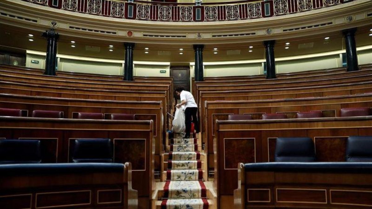 Labores de limpieza en el hemiciclo del Congreso de los Diputados, tras quedarse vacío el pasado 28 de febrero.-EFE / CHEMA MOYA