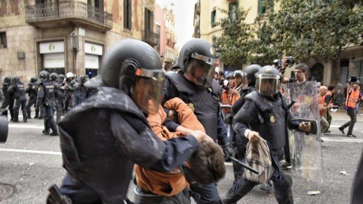 Dos policías con uno de los manifestantes detenidos en Vía Laietana.-MANU MITRU