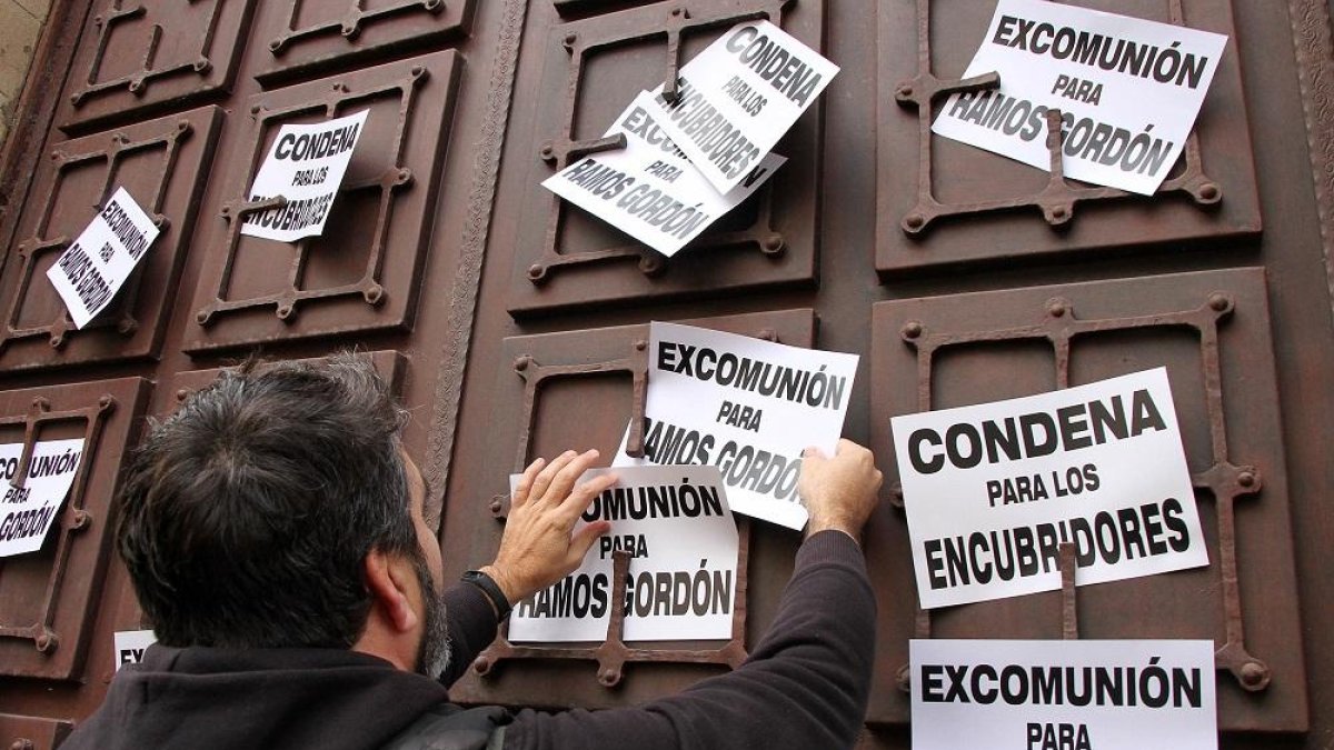 Un manifestante coloca carteles pidiendo la excomunión de RamosGordón y la condena para los encubridores en Astorga.-ICAL