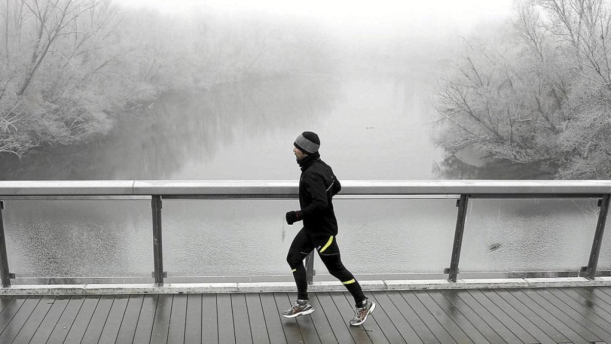 Un hombre corre sobre un puente lleno de cencellada.-ICAL