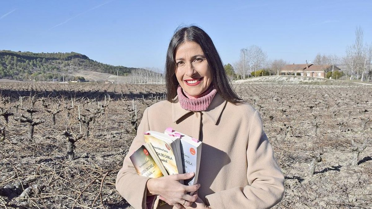 Mayra, con los tres libros que componen su trilogía La vida de Carla en un viñedo de Tudela de Duero, la localidad en la que reside.-