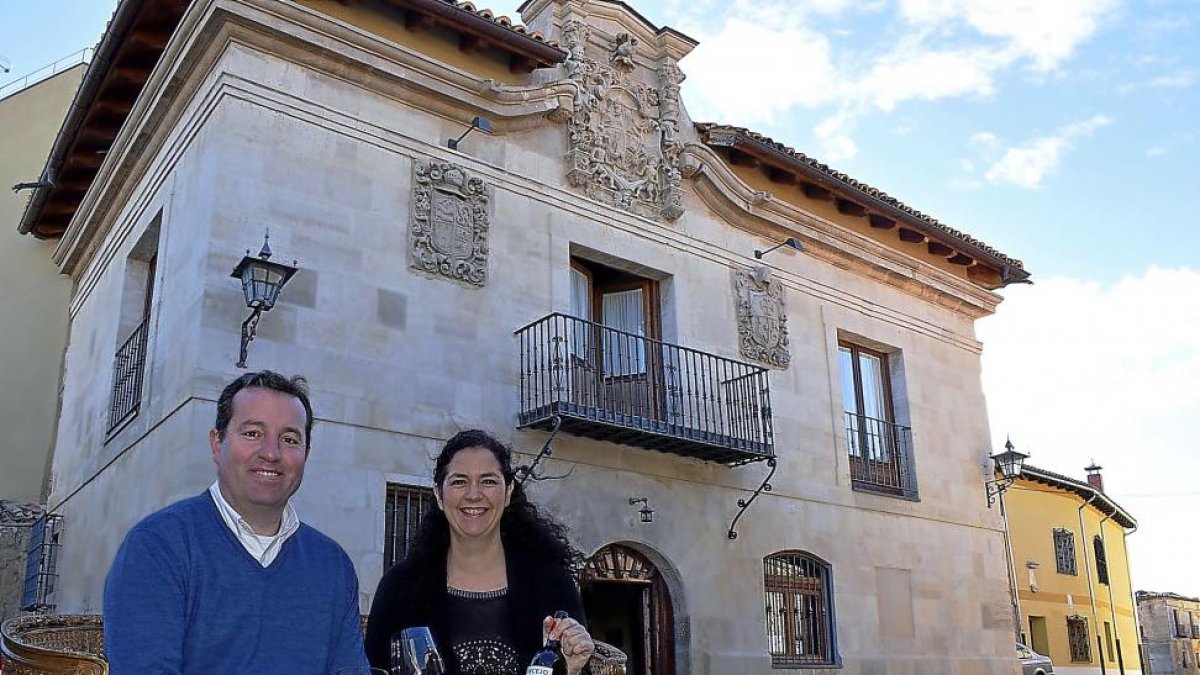 Enrique y Olga, con su tinto cigaleño, ante la fachada del palacio del siglo XVIII, hoy convertido en complejo hostelero en Valoria.-ARGI