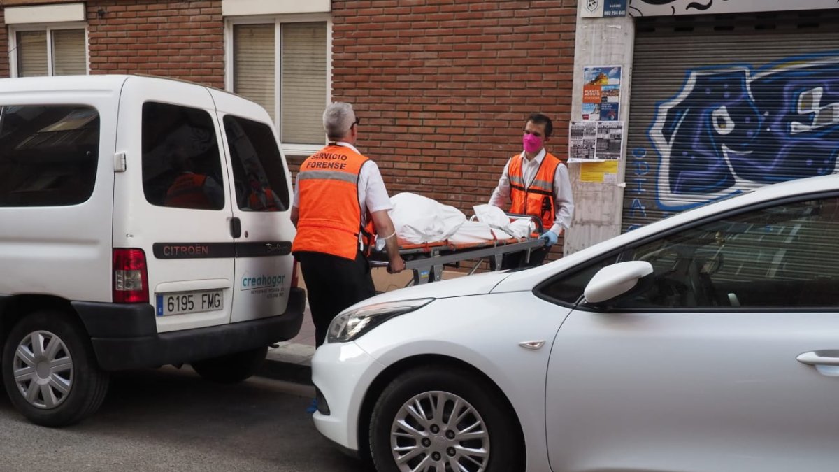 Miembros de servicios forenses sacan el cadáver del edificio.- E.M.