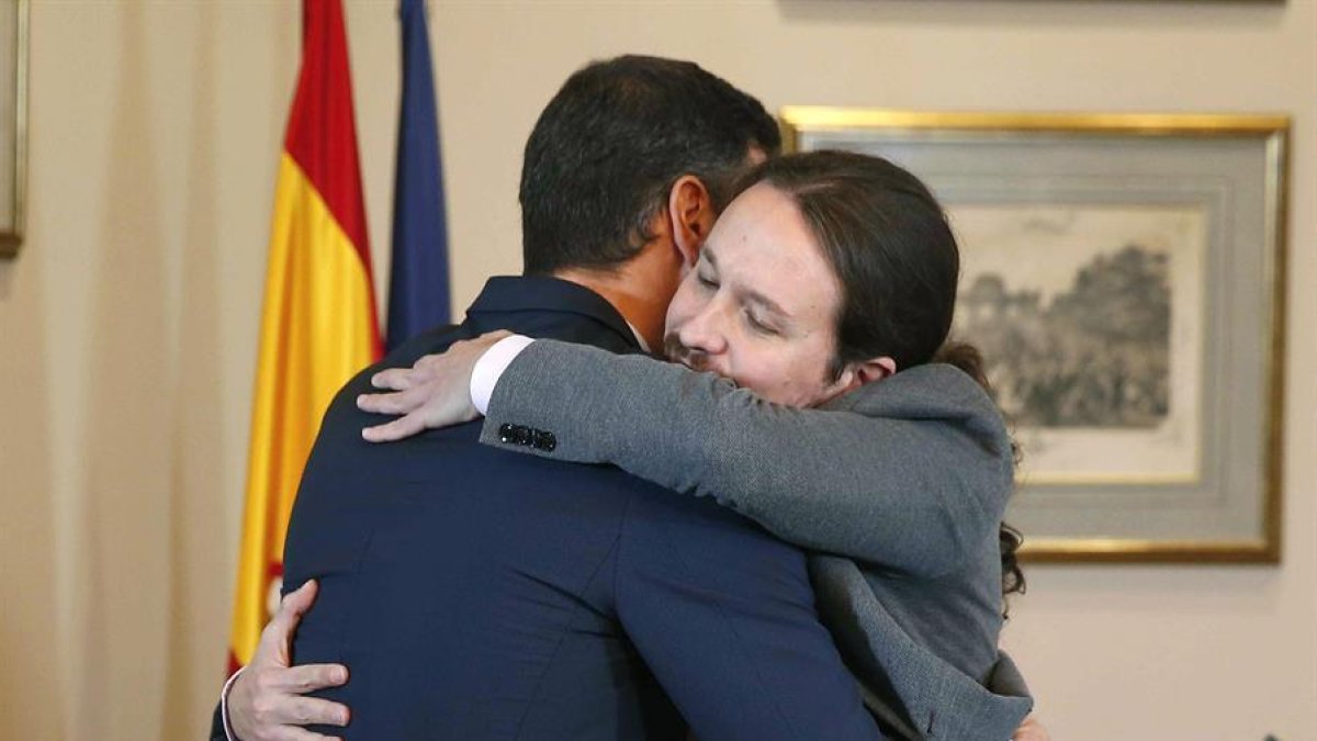 El presidente del Gobierno español en funciones, el socialista Pedro Sánchez, iz., y el líder de Unidas Podemos, Pablo Iglesias,d., se abrazan en el Congreso de los Diputados donde firmaron un acuerdo para la formación de un Ejecutivo en España.-EFE/ PACO CAMPOS