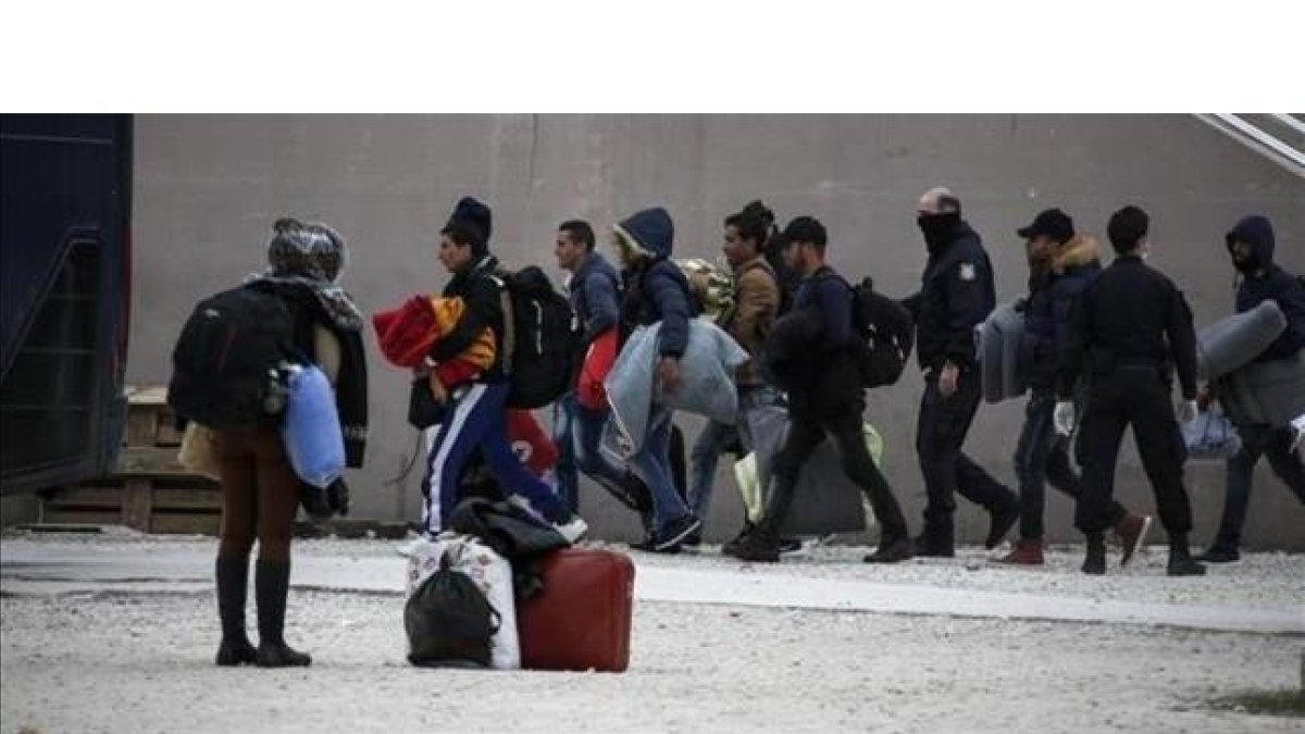La policía griega escolta a inmigrantes en el exterior de un estadio en el sur de Atenas.-AP / YORGOS KARAHALIS.