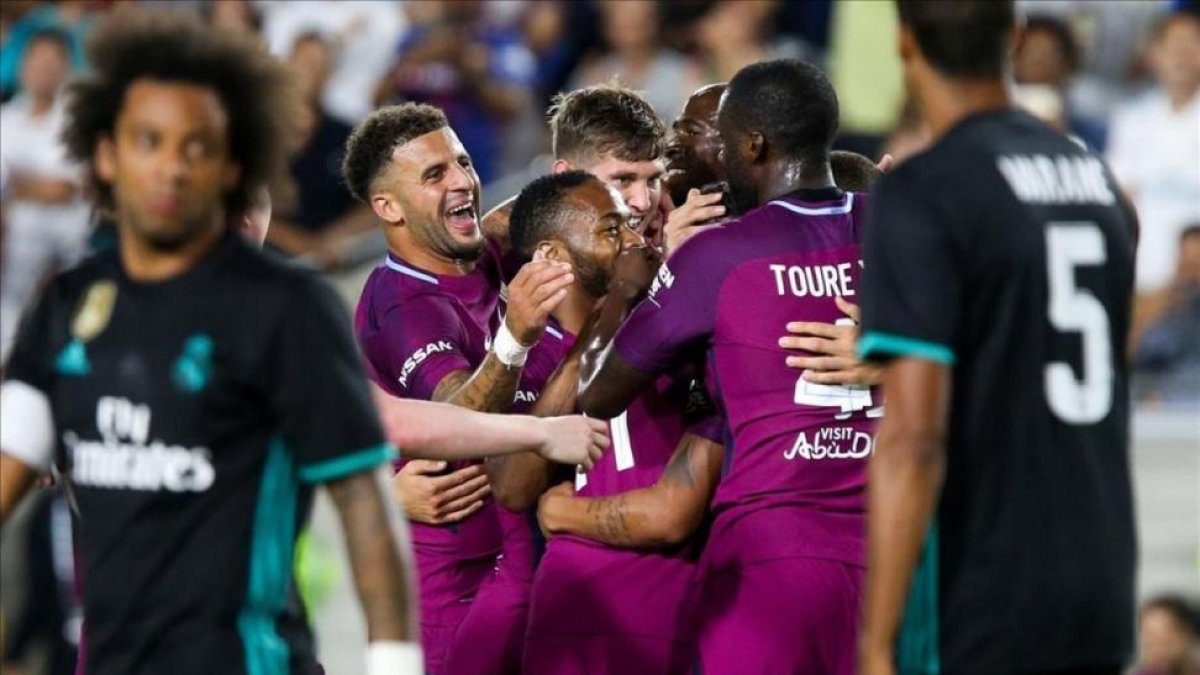 Los jugadores del City celebran un gol ante la mirada de Marcelo y Varane.-AFP / RINGO CHIU