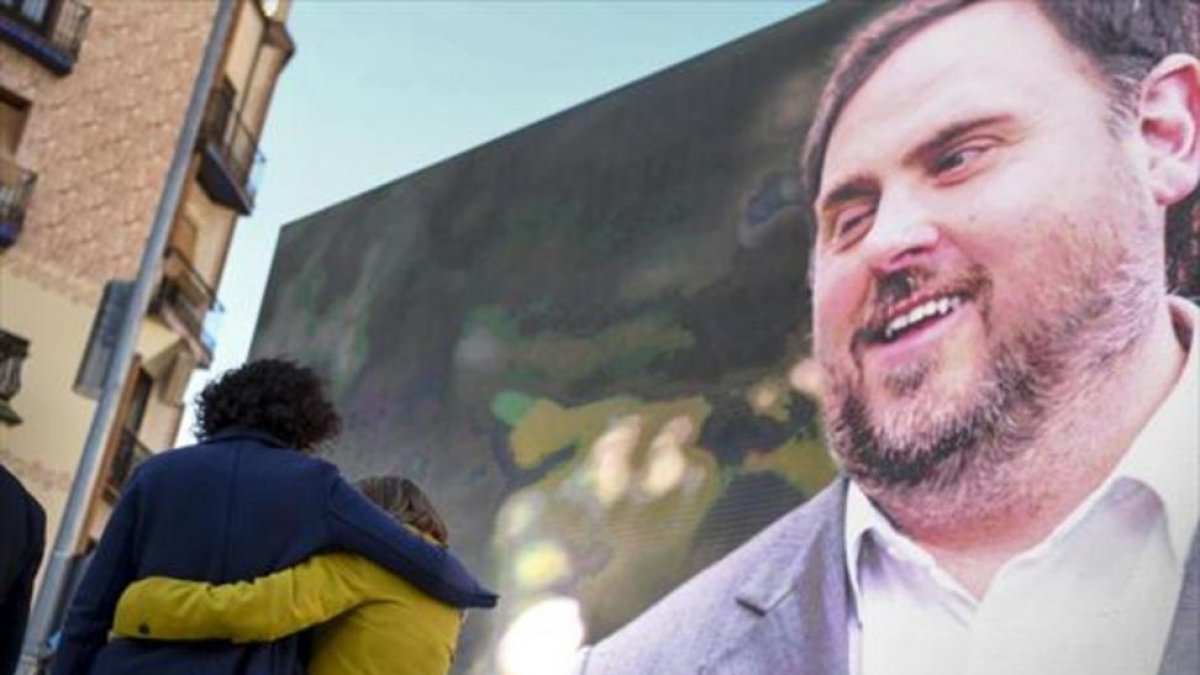 Marta Rovira se abraza a la también candidata Carme Forcadell bajo la mirada de Oriol Junqueras desde la pantalla, en el acto central en el Born.-JORDI COTRINA